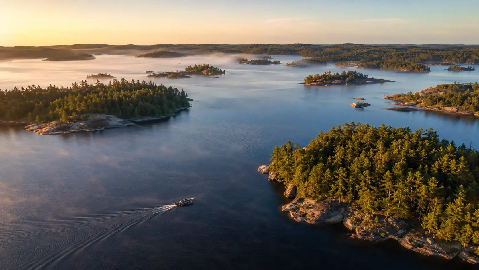 Aerial view of a blue Ontario lake with forested islands and a fishing boat